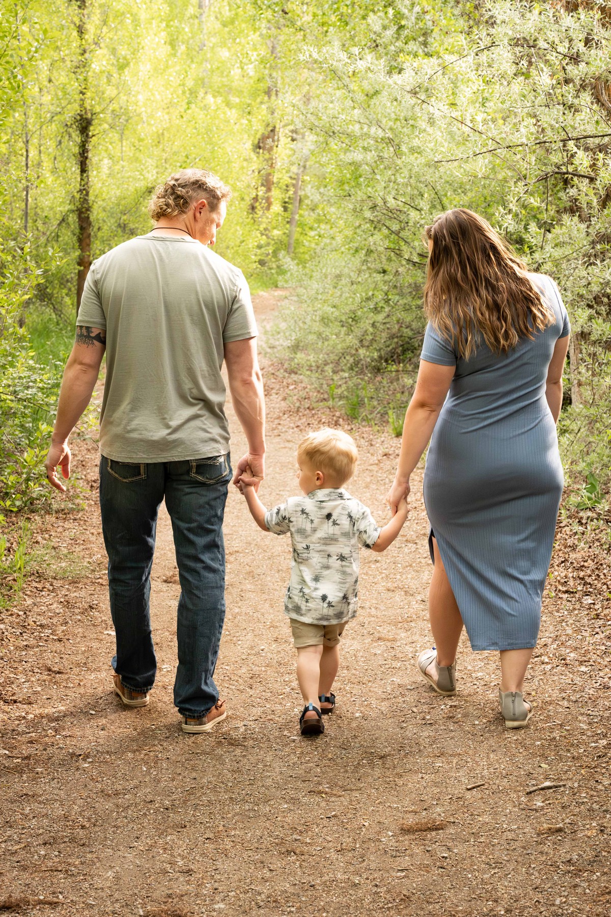 Family walking hand in hand through a green path by Jen Kunz Photography