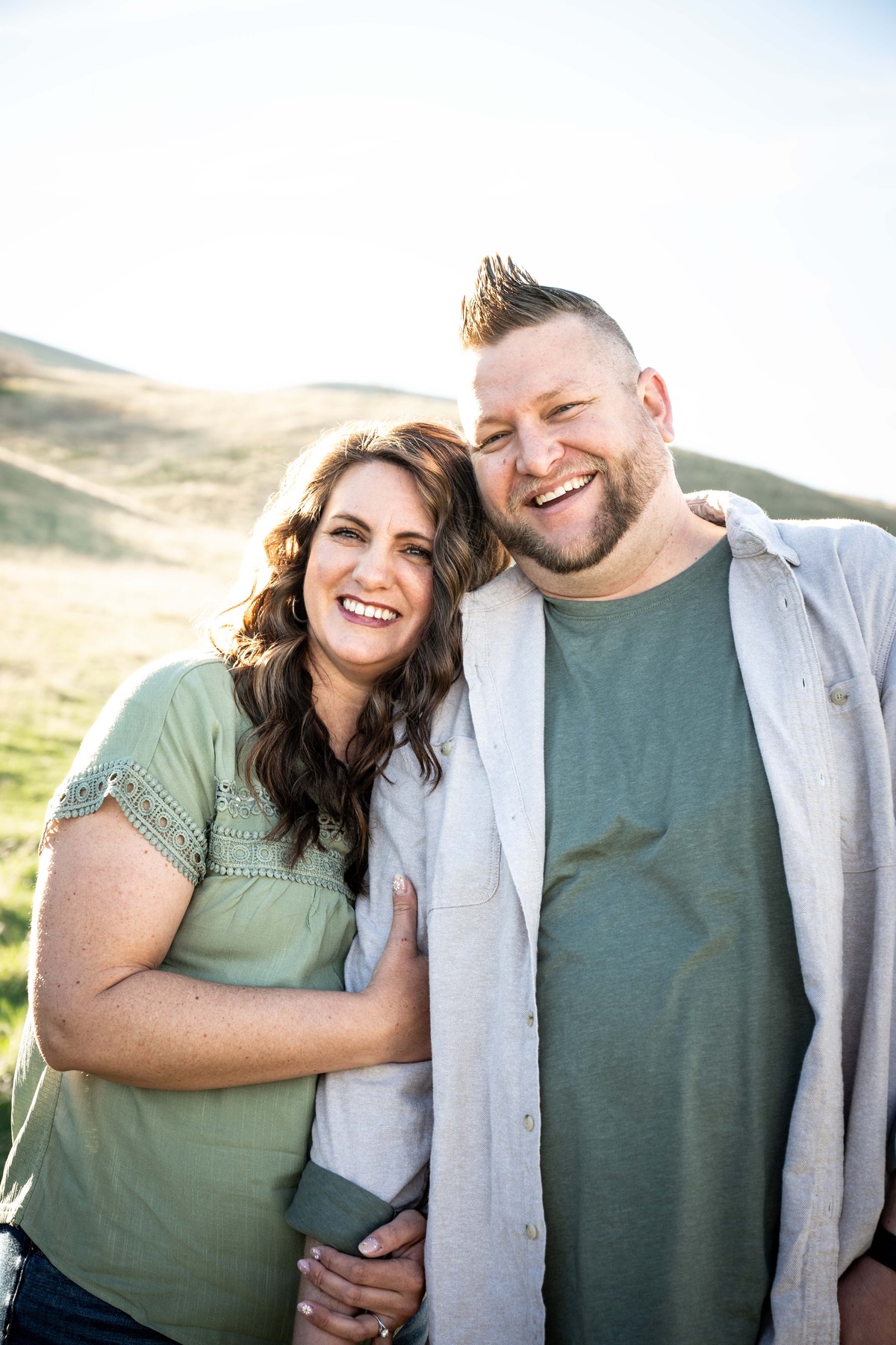 Smiling couple standing together outdoors with hills behind them